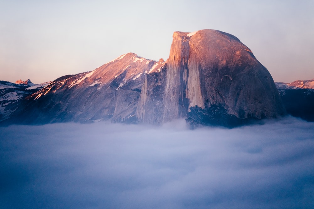 brown mountain near white clouds at daytime