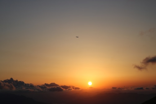 A drone capturing a golden hour wedding scene by the Adriatic coast, with the sun casting warm light over the ocean and couple.