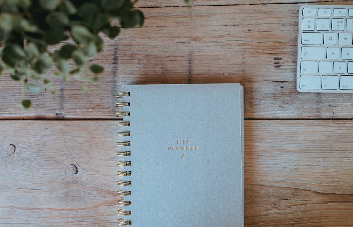 Gray notebook on a wooden table, open to a page with handwritten notes about organizing fall events with online sign-ups.