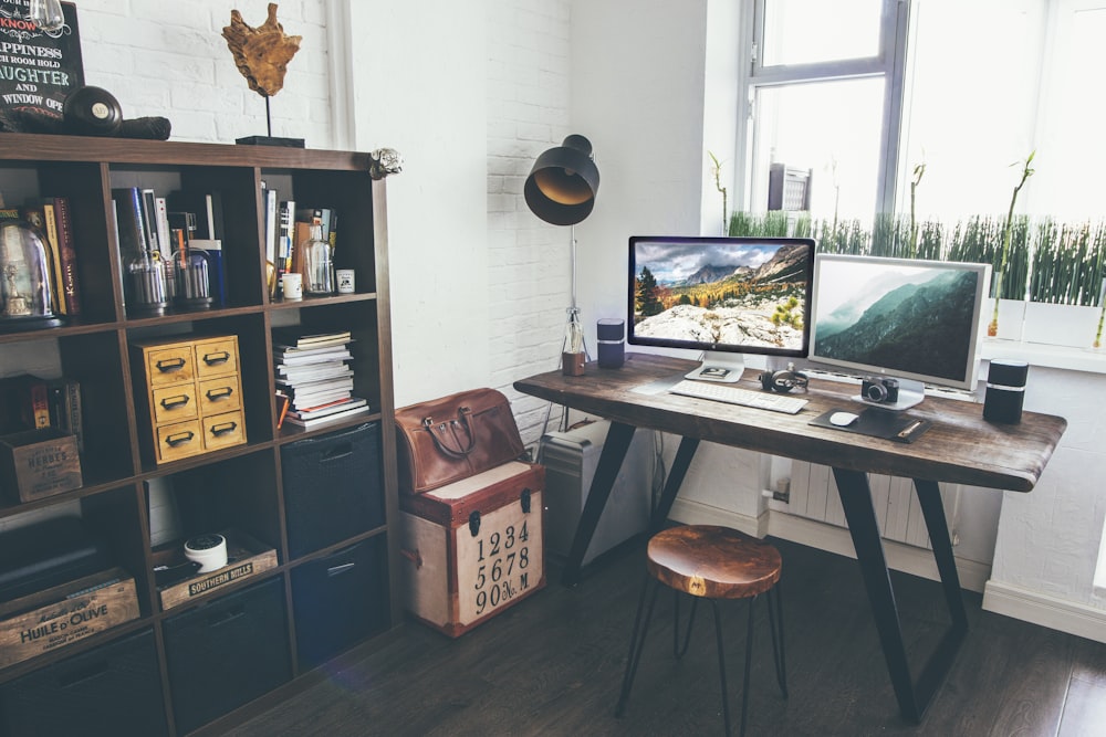 Dos monitores de pantalla plana encendidos cerca del estante organizador dentro de la habitación