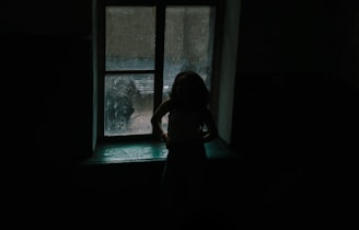 A shadowy figure standing alone in a dimly lit room, creating a mysterious and suspenseful atmosphere.