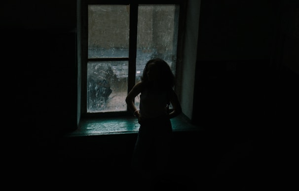 A shadowy figure standing alone in a dimly lit room, creating a mysterious and suspenseful atmosphere.