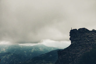 An epic scene of a hero standing on a cliff overlooking a vast, mystical landscape.