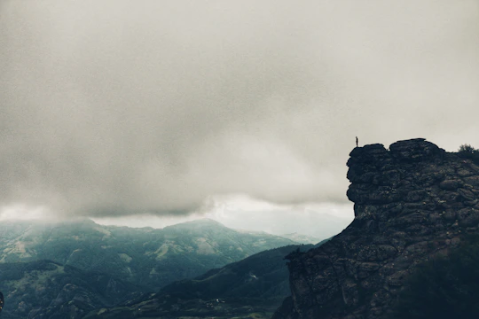 An epic scene of a hero standing on a cliff overlooking a vast, mystical landscape.