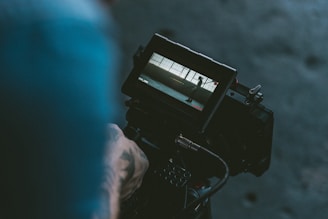 person holding black shoulder-mount video camera