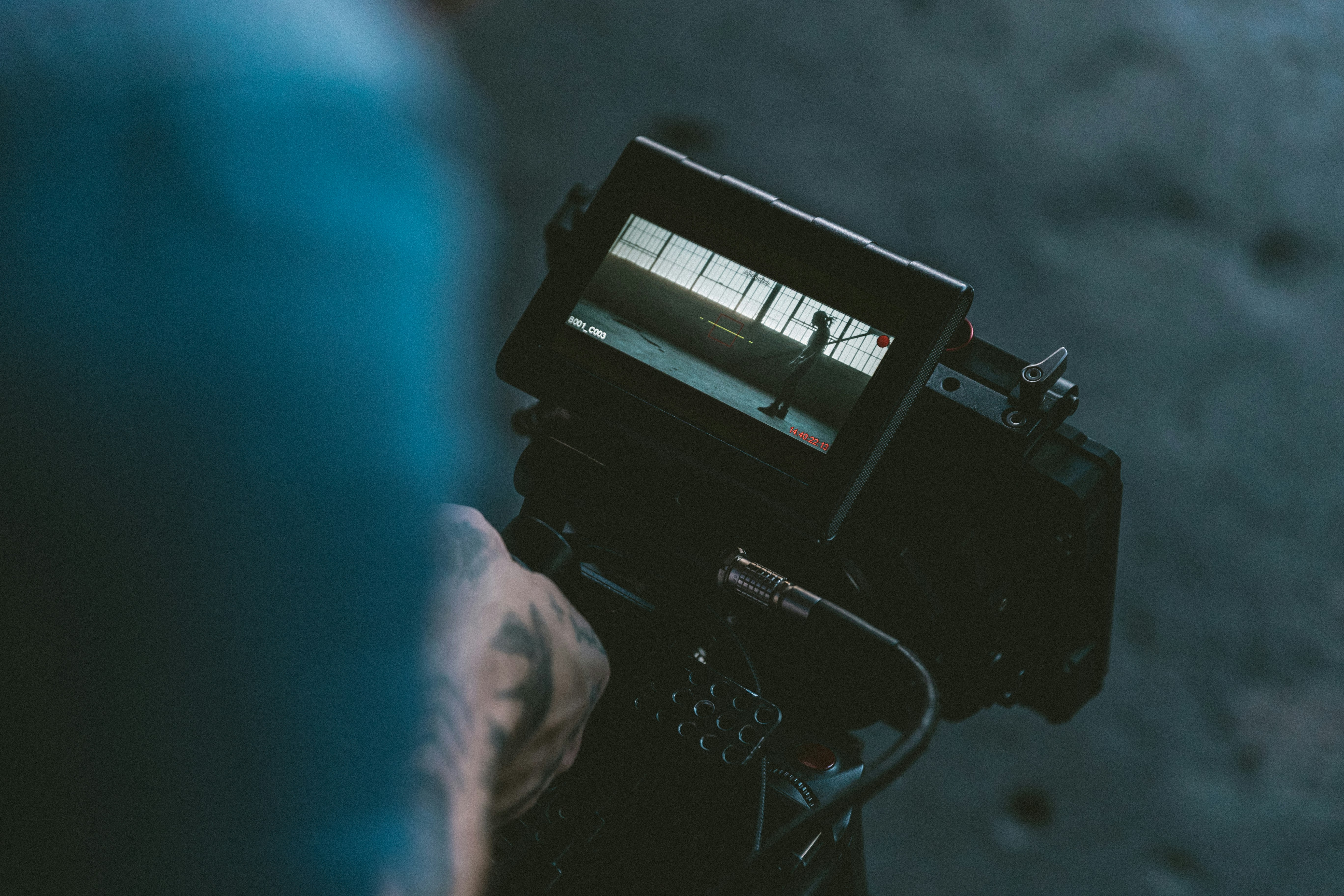 person holding black shoulder-mount video camera