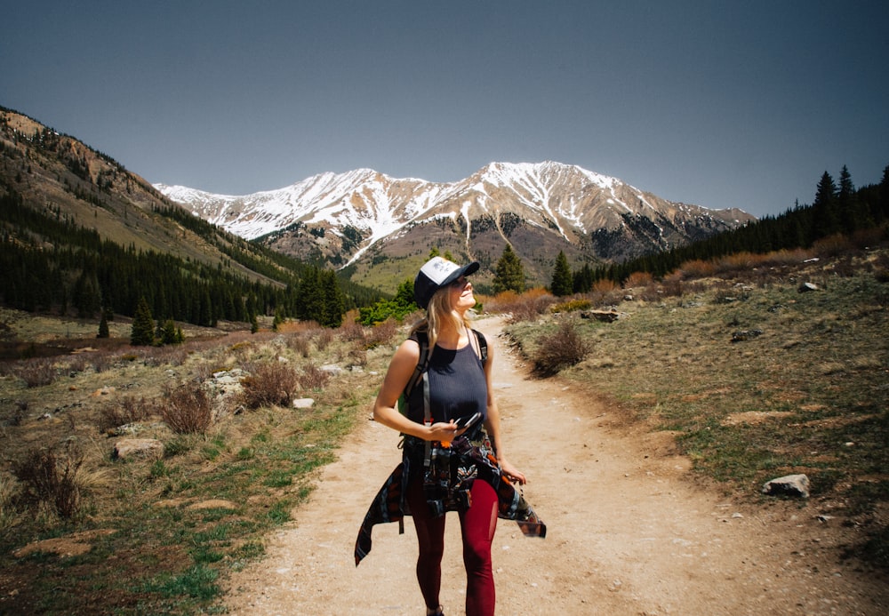 woman walking on brown road holding camera