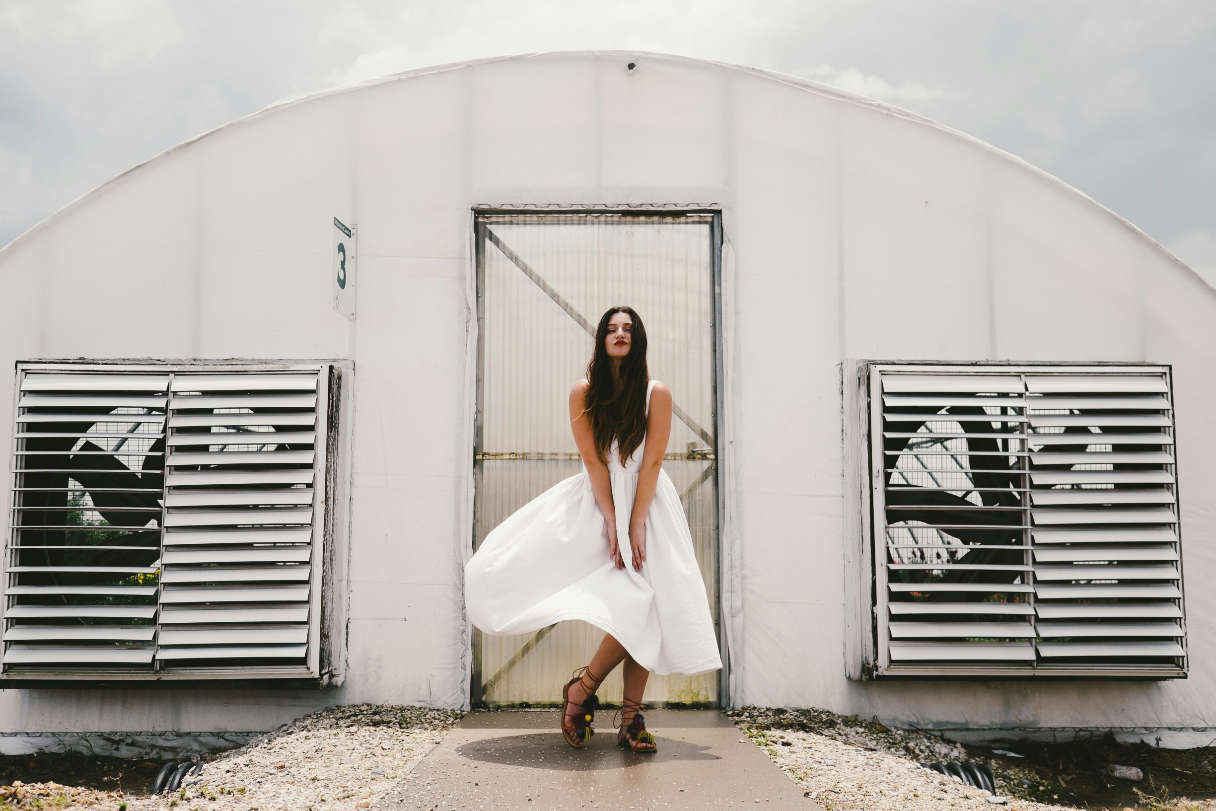 woman wearing white dress standing in front of white enclosure during daytime