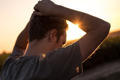 man holding his hair against sunlight upset teams background