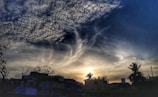 A twilight sky with surreal floating clouds shaped like human profiles blending with digital circuits
