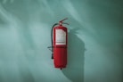 red fire extinguisher on green wall