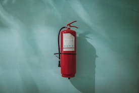 red fire extinguisher on green wall