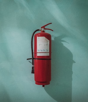 red fire extinguisher on green wall