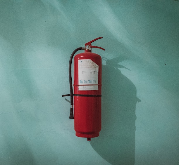 red fire extinguisher on green wall