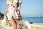 woman walking on seaside while holding woven bag