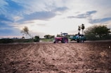 A modern tractor working in a lush green field during sunrise