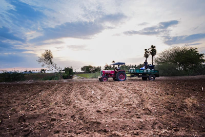 A vibrant tractor working in a lush green field under a clear blue sky
