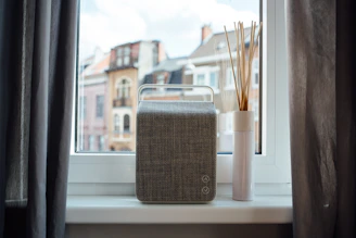 A sleek pack of Vivatela facial tissues resting on a minimalist city apartment windowsill.