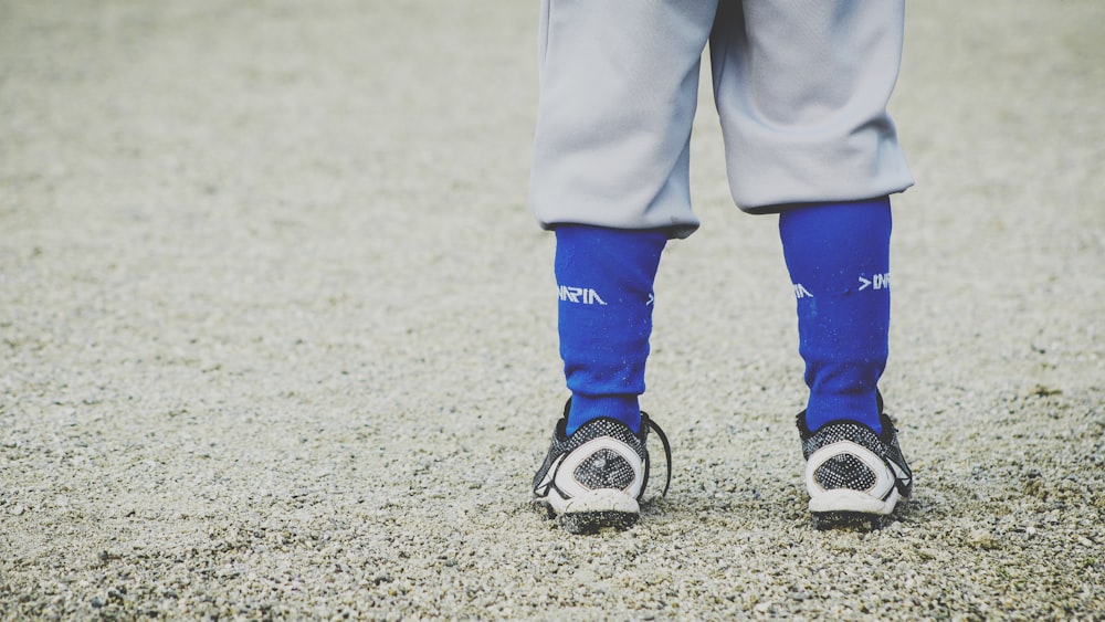 persona che indossa scarpe bianche sotto il cielo soleggiato