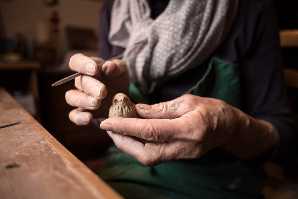 persona sosteniendo artesanía de madera de pájaro