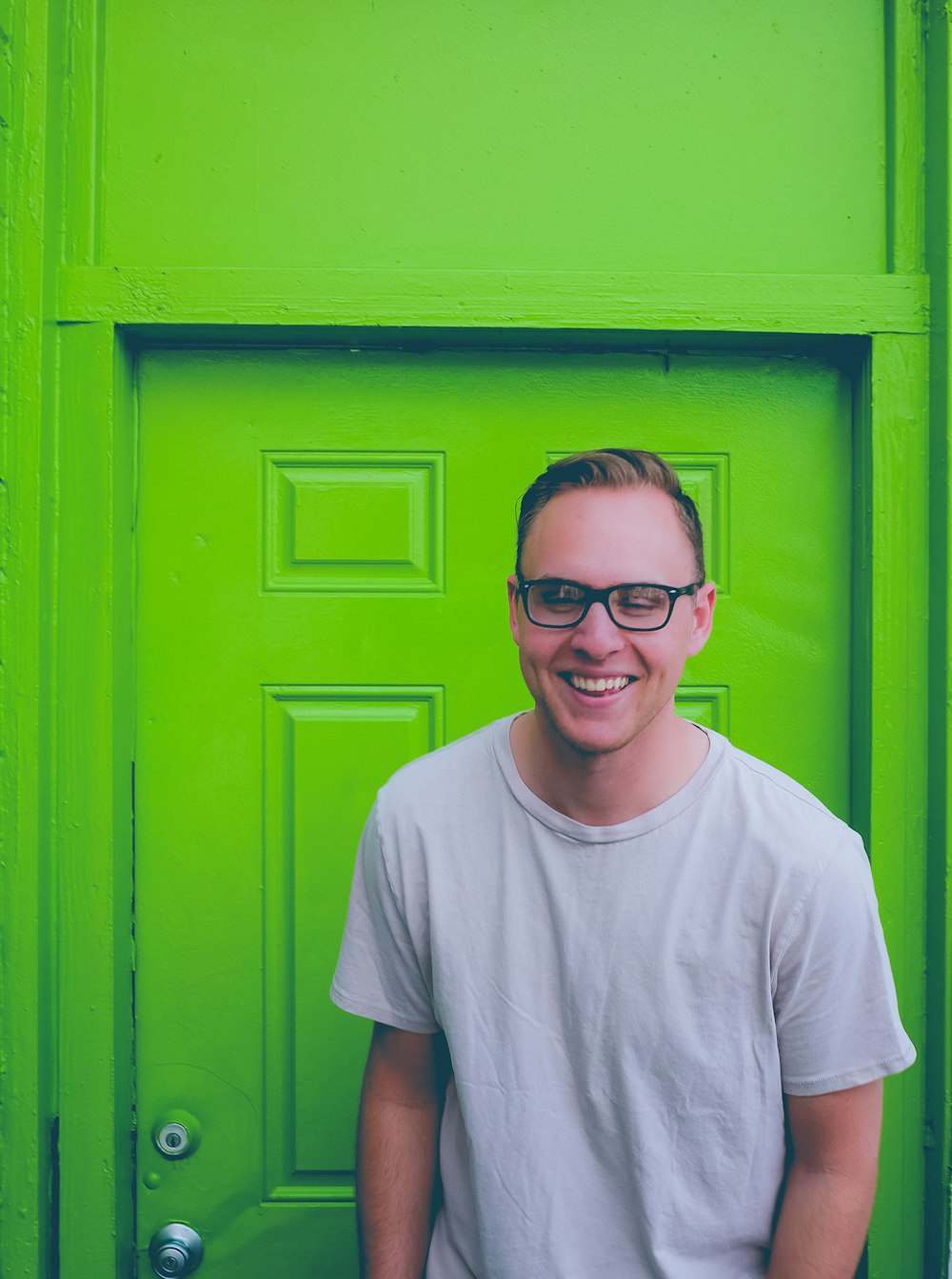 unknown person in white crew-neck top standing near green door