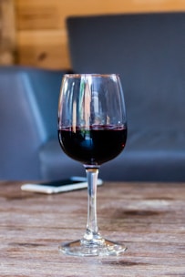 An elegant wine bottle on a rustic wooden table, with a smartphone displaying an audio message.