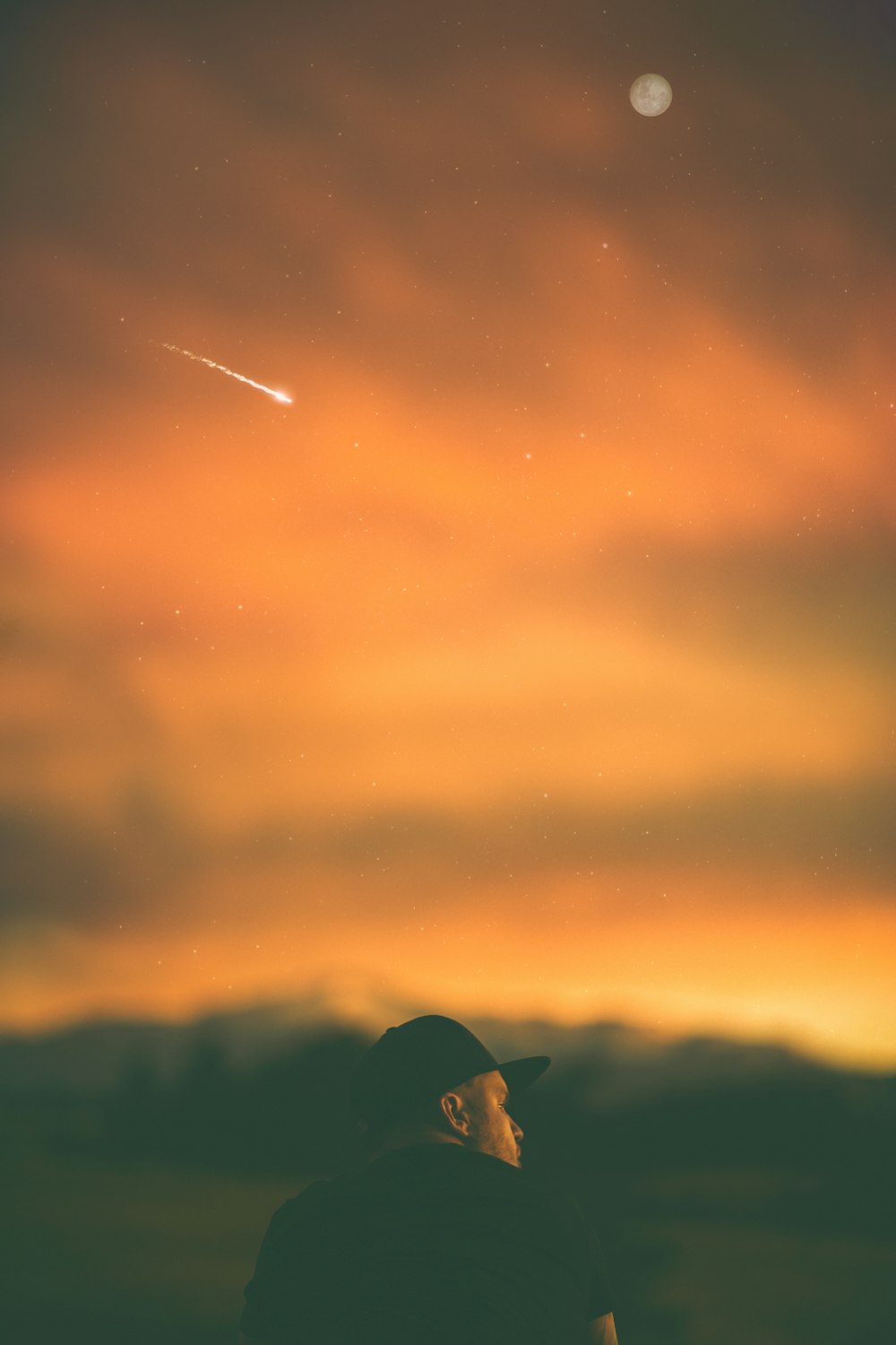 man wearing black fitted cap under orange clouds