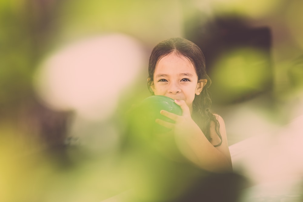 girl blowing green balloon