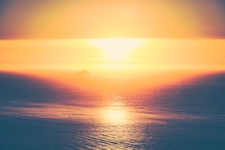 A serene sunrise over a vast ocean with a merchant navy ship sailing steadily.