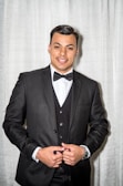A groom in a classic black tuxedo with a bow tie.