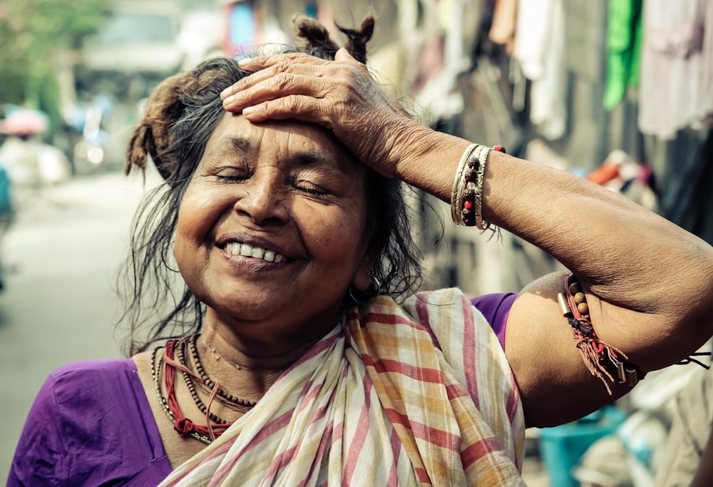 closeup photo of smiling woman holding her forehead