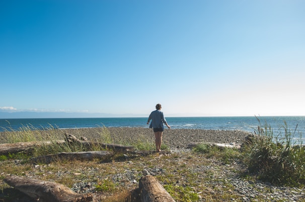 A serene person standing strong on a rocky shore, facing the waves with calm determination.