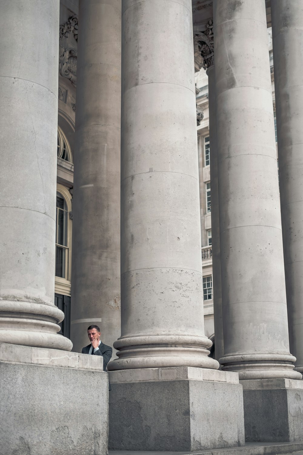 man standing beside gray concrete pillars