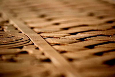 Artisan carving intricate patterns into rich wooden handicrafts under warm light.