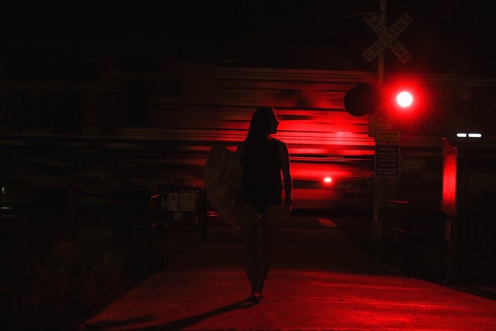 man in brown jacket and black pants carrying brown backpack walking on pedestrian lane during night