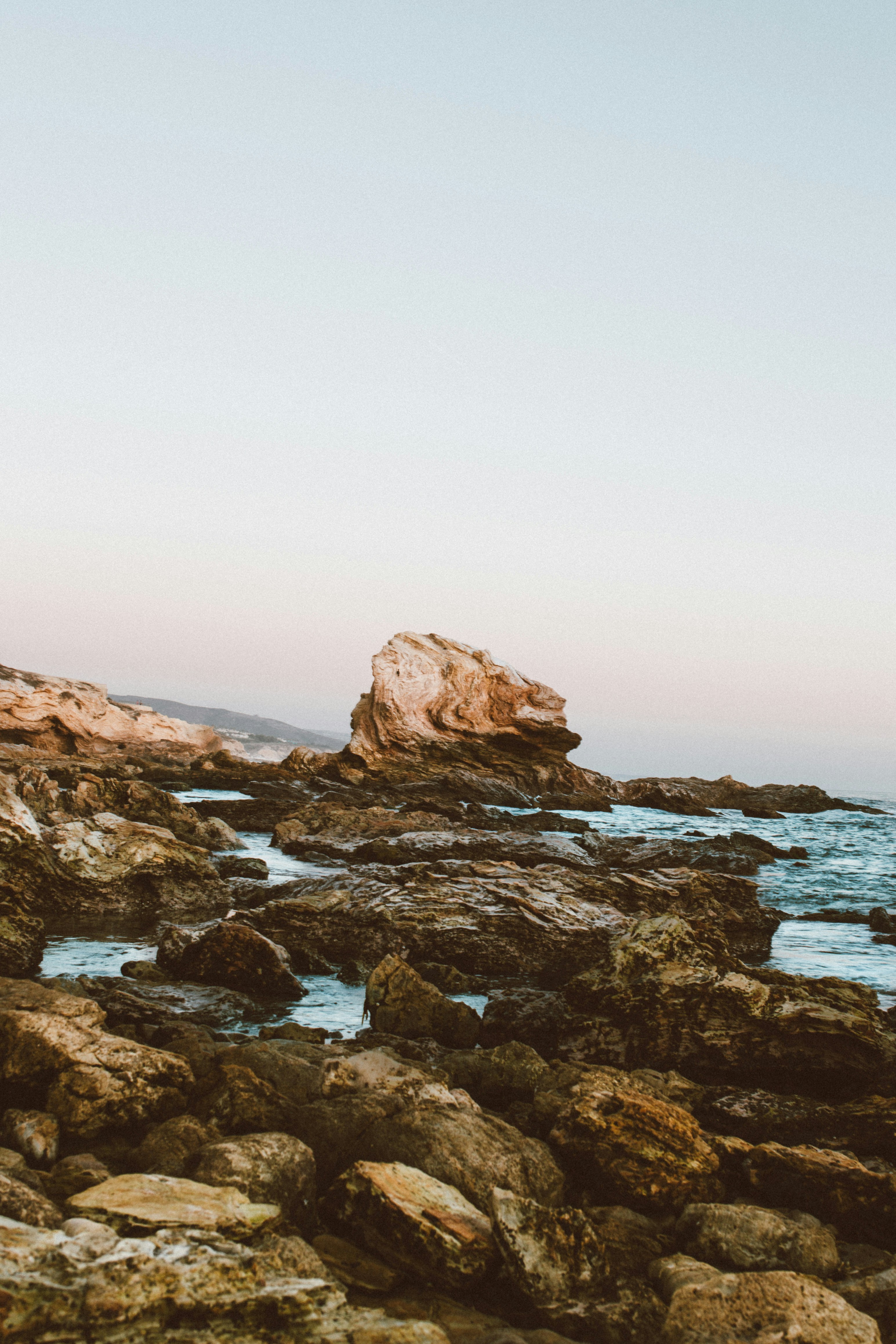 Rocky coastline with ocean waves and a large rock formation.