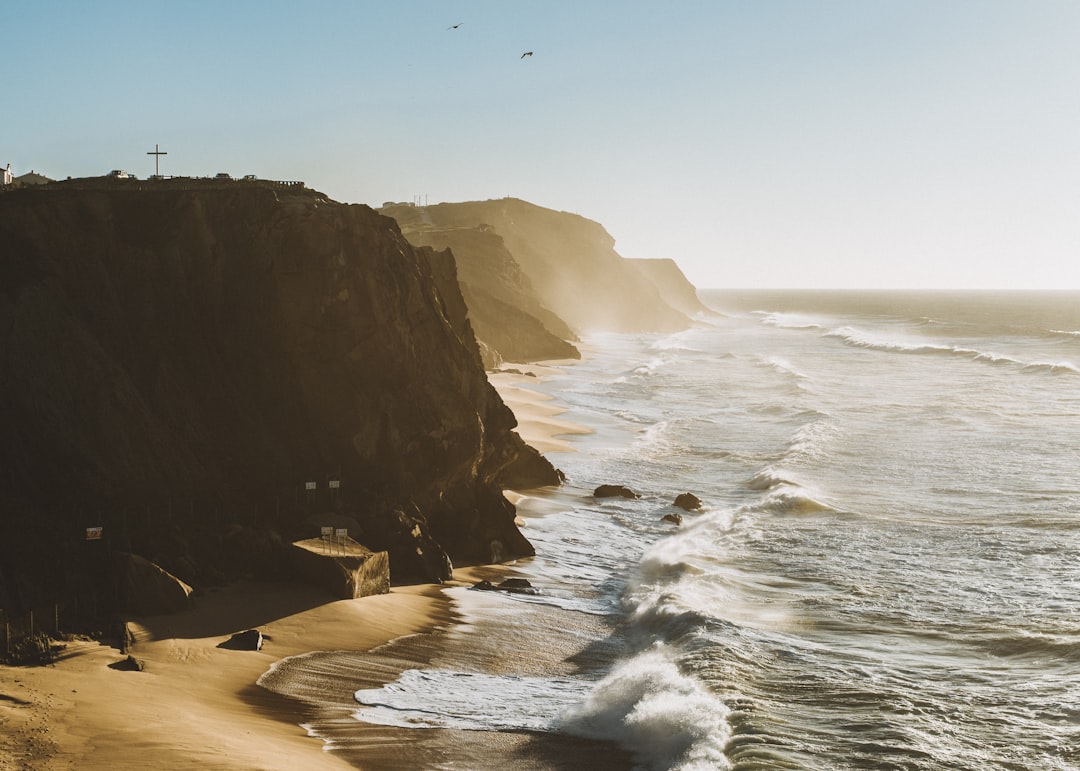 seashore mountain during day time, Ocean crashing on beach