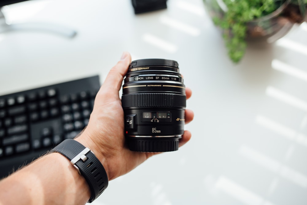 persona sosteniendo la lente de la cámara DSLR