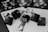 A series of playing cards and poker chips are displayed. The cards, including a ten, jack, queen, king, and ace of clubs, are spread out with black keyboard keys arranged to spell the word 'POKER'. The image is in black and white, giving it a classic, stylish look.