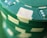 A close-up view of a stack of green poker chips with white accents and indented designs around the edges.