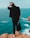 man standing on top of mountain facing backwards at body of water