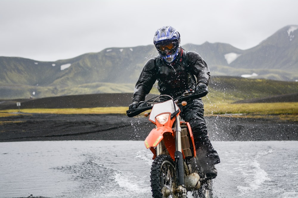 person riding dirt motorcycle on body of water during daytime