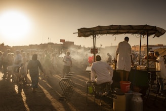 A vibrant street food market at sunset with colorful stalls and people enjoying local dishes.