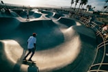 A wide shot of an outdoor skatepark filled with active skaters at dusk.