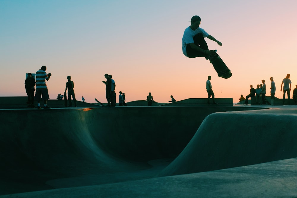 Homem fazendo truque no skate park durante o pôr do sol