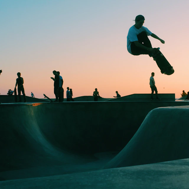 A man doing a trick at a skateboard park during sunset