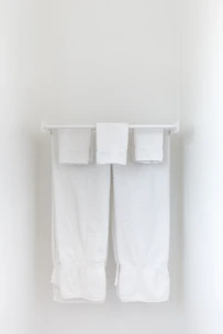Brass wall-mounted towel rack holding neatly folded towels against a light-colored wall.