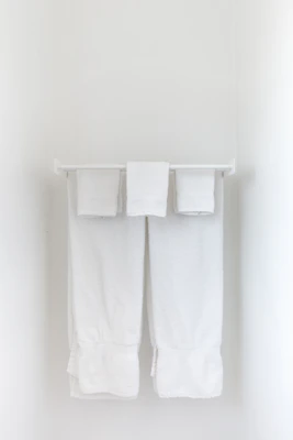 Brass wall-mounted towel rack holding neatly folded towels against a light-colored wall.