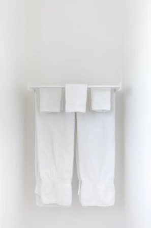 Brass wall-mounted towel rack holding neatly folded towels against a white tile wall.