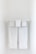 Two neatly folded white towels hang from a clean, white towel rack against a plain, light-colored wall.